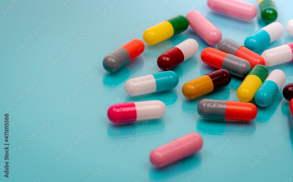 Antibiotic capsule pills on blue background. Prescription drugs. Colorful capsule pills. Antibiotic drug resistance concept. Pharmaceutical industry. Superbug problems. Medicament and pharmacology. Antibiotic capsule pills on blue background. Prescription drugs. Colorful capsule pills. Antibiotic drug resistance concept. Pharmaceutical industry. Superbug problems. Medicament and pharmacology.