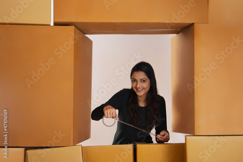 Adult girl packing cardboard box with cello tape photo