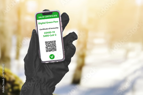 Hand In Ski Glove Holding Smartphone With Digital Green Pass Qr Code Against Snowy Winter Landscape. Health Passport, Certificate Of Immunity. Sport Tourism Without Restrictions.