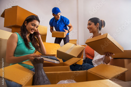 Girls packing household goods and handing over box to the boy for stacking