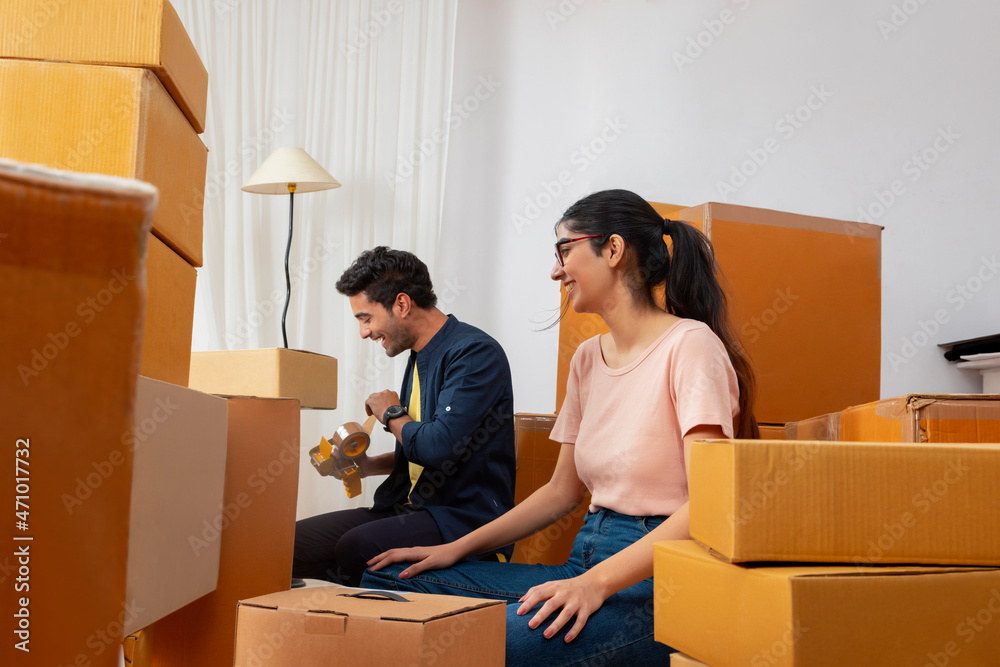 Adult boy and girl smiling together during packing of carton boxes Adult boy and girl smiling together during packing of carton boxes