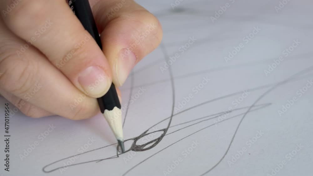 Close-up of a pencil in hand which draws lines on a sheet of paper. Designer work on paper using a pencil. The artist draws a sketch on paper. Neurography and therapy. Close-up of a pencil in hand which draws lines on a sheet of paper. Designer work on paper using a pencil. The artist draws a sketch on paper. Neurography and therapy.