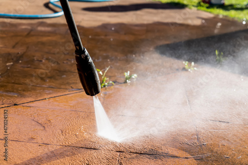 Cleaning dirty backyard paving tiles with pressure washer cleaner. photo