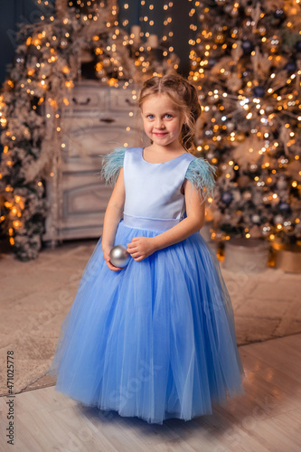 beautiful girl in an elegant dress against the background of Christmas lights and a Christmas tree in a beautiful interior
