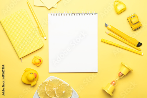 yellow pills, yellow rubber ducks, a pen, a yellow mini car and lemon slices and a white sheet of paper in a planning notebook on a yellow background