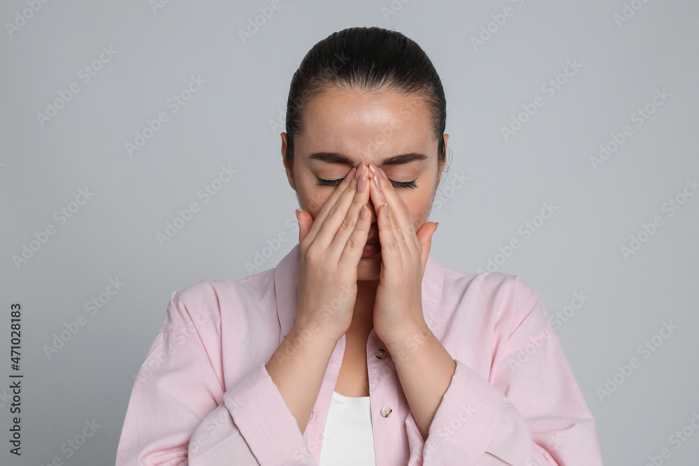 Young woman suffering from headache on light grey background