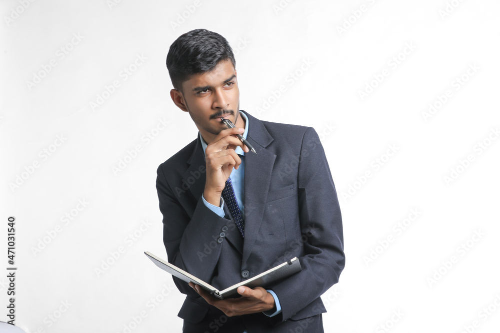 Young indian man holding diary in hand and thinking some idea Young indian man holding diary in hand and thinking some idea