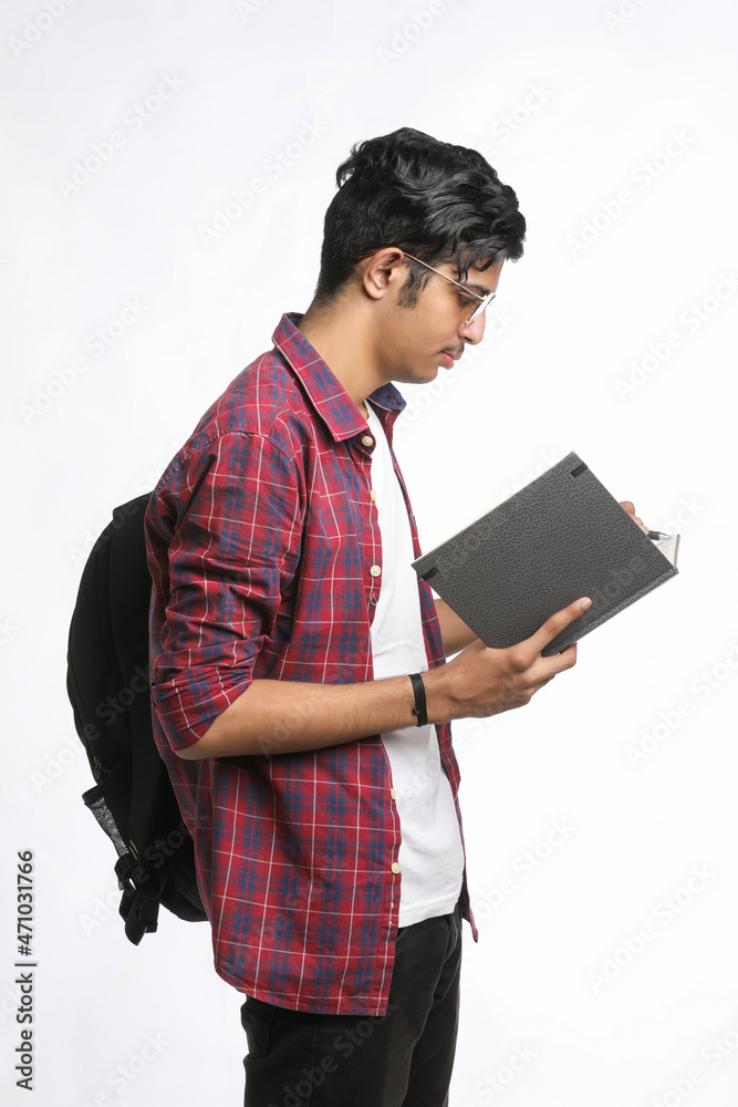 Indian college student standing with bag and reading dairy over white  background. Stock Photo | Adobe Stock