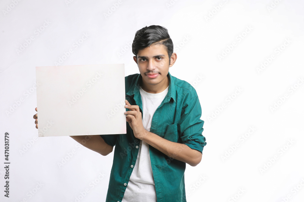 Young Indian man showing blank sing board over white background. Young Indian man showing blank sing board over white background.
