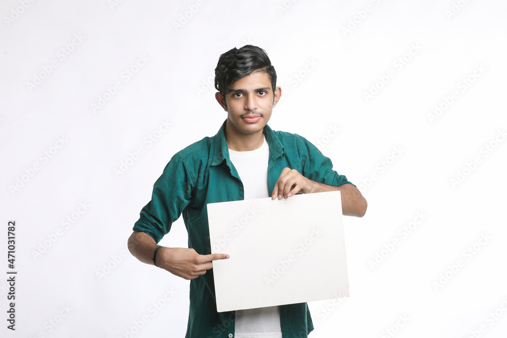 Young Indian man showing blank sing board over white background. Young Indian man showing blank sing board over white background.