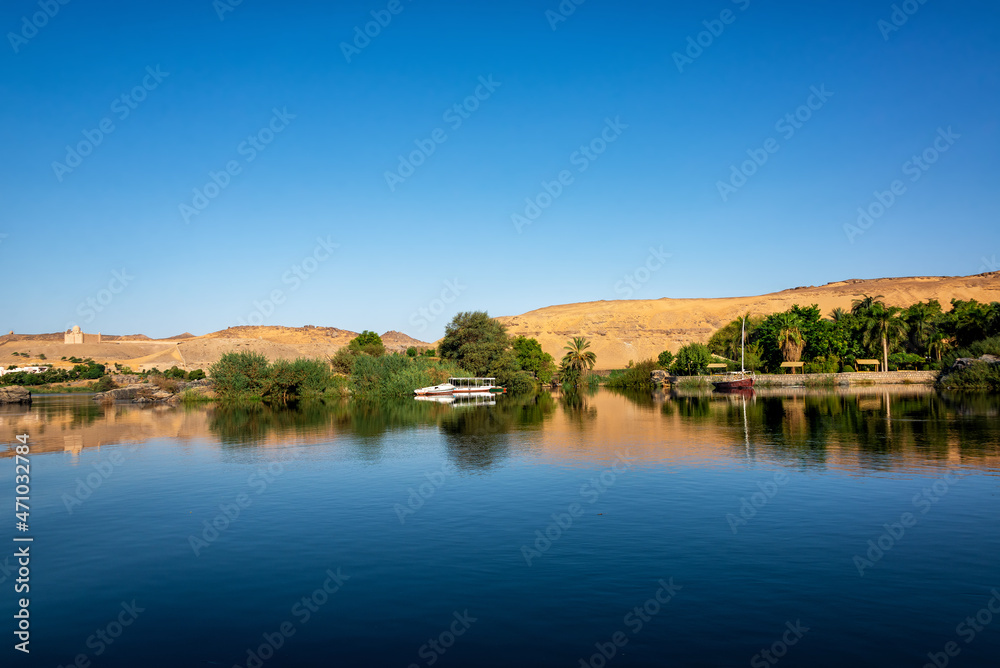 Sand dunes and palm trees reflected in the Nile River in Aswan, Egypt Sand dunes and palm trees reflected in the Nile River in Aswan, Egypt