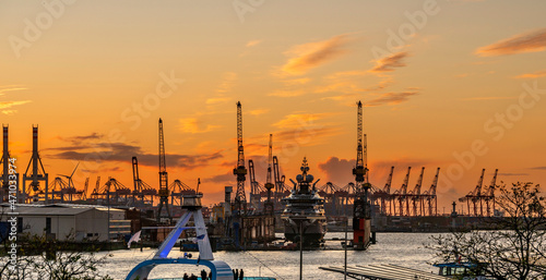 Blick auf den Hamburger Hafen mit Kränen, Werft und Superyacht nach Sonnenuntergang photo