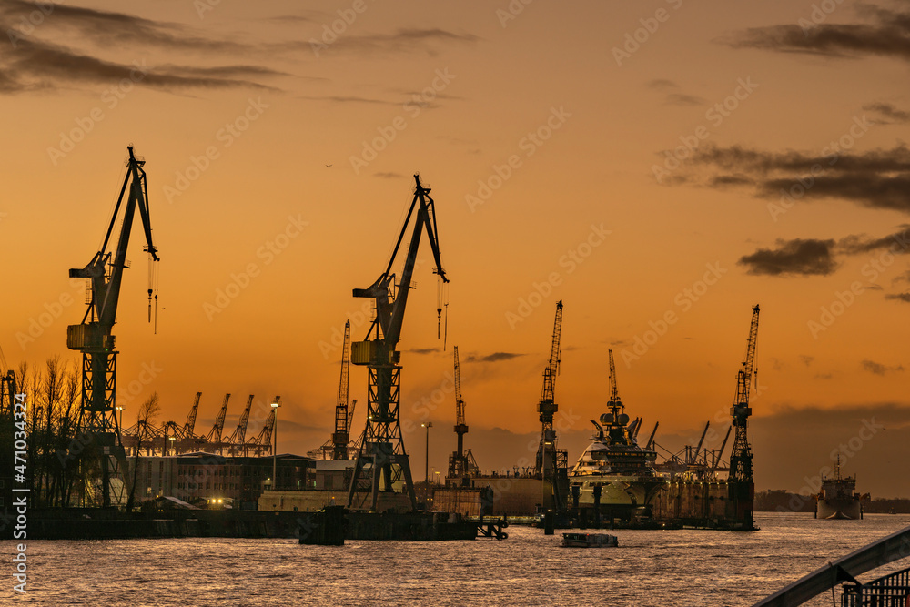 View to the river Elbe in Hamburg with cranes, dock and super-yacht after sunset with afterglow