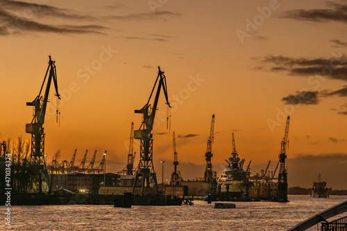 View to the river Elbe in Hamburg with cranes, dock and super-yacht after sunset with afterglow