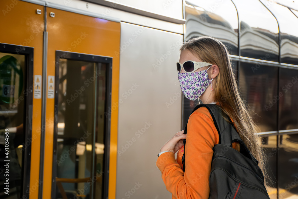 Foto de Teenage girl wearing face mask waiting for the train on the
