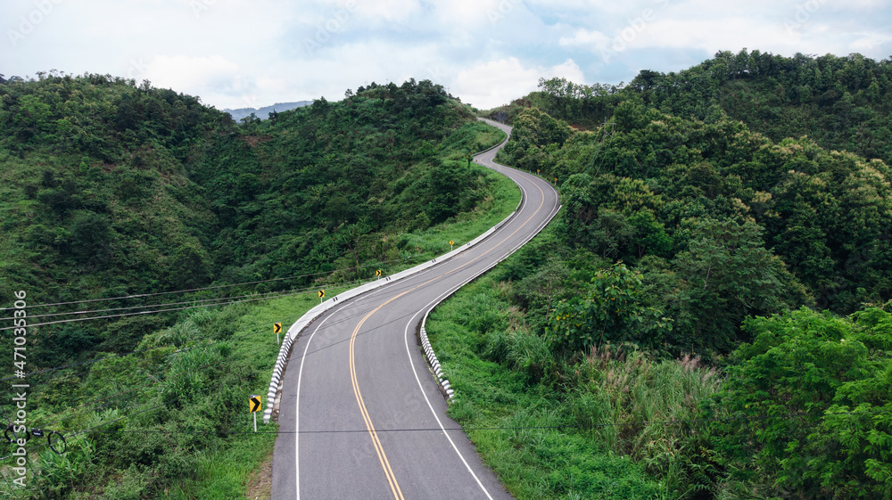 Aerial view of winding road shaped like 3 on top of mountain in tropical rainforest at Nan province