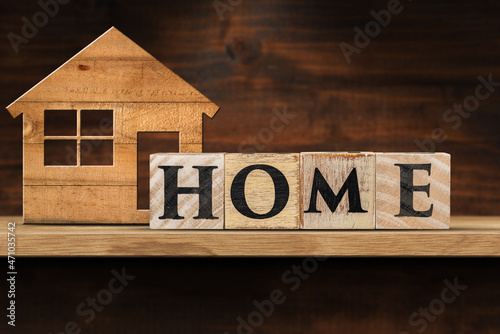Text Home made of wooden blocks and a small model house on a wooden shelf with copy space.