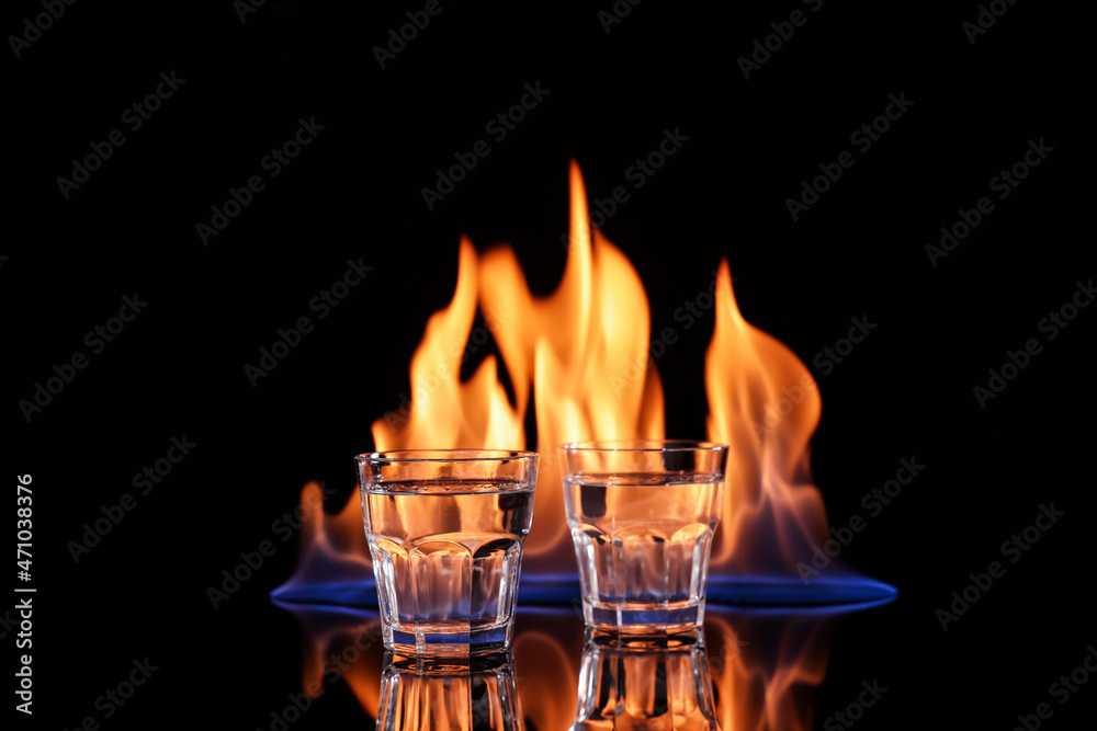 Vodka in glasses and flame on black background