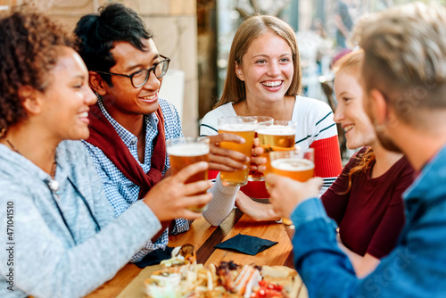 Fotografering Group of diverse young friends enjoying a beer together