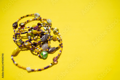 Happy stones necklace or bracelet on the sunny yellow table. Copy space.