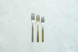 silver stainless steel metal forks and another gold one with different textures on white marble table