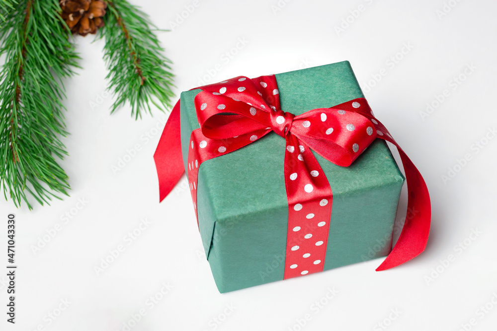 Christmas gift box with red bow and pine tree branch on white