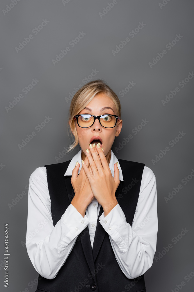 Shocked businesswoman in eyeglasses looking at camera isolated on grey Shocked businesswoman in eyeglasses looking at camera isolated on grey