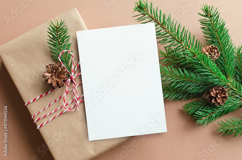 Christmas greeting card mockup with decorated gift box and fir tree branches with cones
