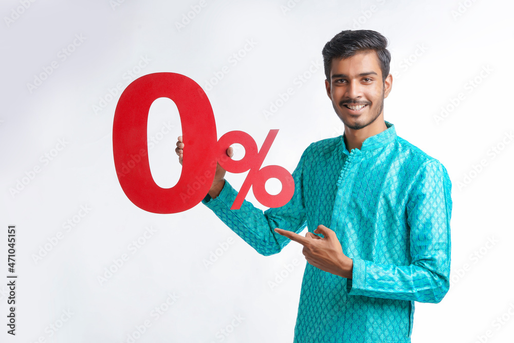Indian man holding zero percent sign board promoting offers on festival season while wearing traditional cloths, standing over white background. Indian man holding zero percent sign board promoting offers on festival season while wearing traditional cloths, standing over white background.