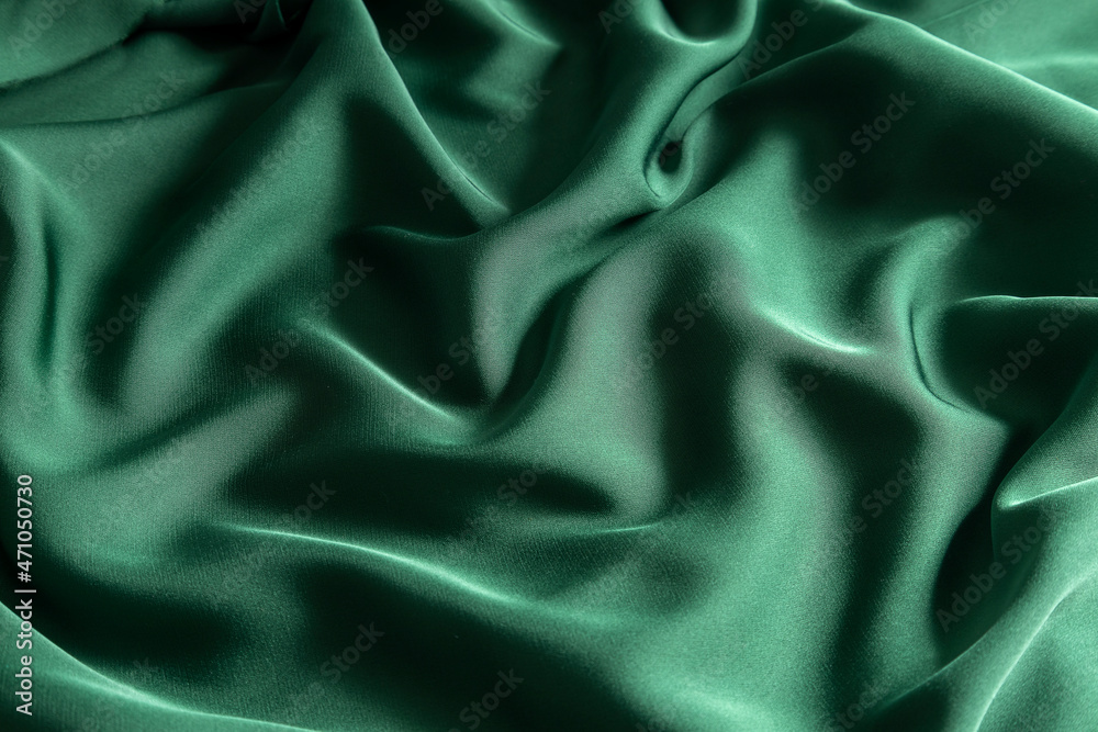 Fototapeta premium Closeup of stylish green silk waves.Preparation fabric for sewing evening garment.