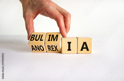 Bulimia or anorexia symbol. Doctor turns wooden cubes and changes the word anorexia to bulimia. Beautiful white table, white background, copy space. Medical, bulimia or anorexia concept. photo