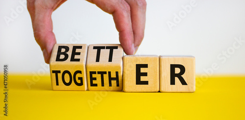 Better together symbol. Businessman turns cubes and changes the word together to better. Beautiful yellow table, white background, copy space. Business, motivational and better together concept. photo