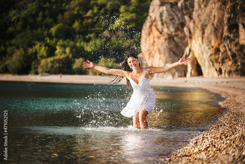 Girl splashes water on a paradise beach in the water. An atmosphere of fun and carefree. 