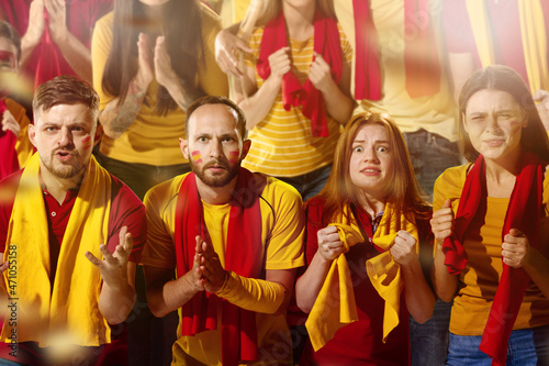 Spanish football, soccer fans cheering their team with yellow and red scarfs at stadium. Concept of sport, emotions, team event, competition.