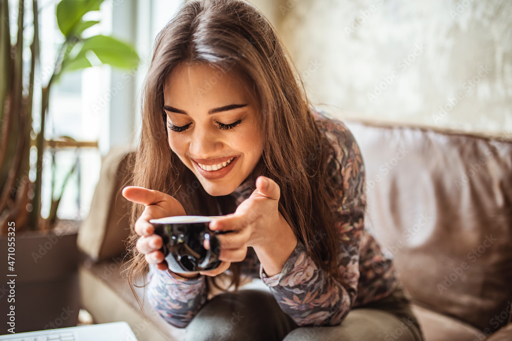 portrait of young woman drinking coffee at table in cafe. Side view of Happy brunette woman drinking coffee and looking at the camera. Beautiful smiling woman drinking coffee at cafe. 