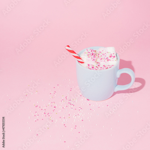 Christmas creative layout with a pastel blue cup and frothy sweet candies and sweets. Minimal holiday sweet concept with marshmallows on pastel pink background.