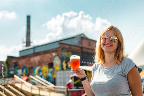Billede på lærred Smiling blonde girl in sunglasses drinking amber ale beer at the summer festival