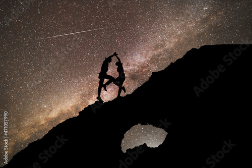 The copuple dancing on the clif in the starry night with brigt milky way galaxy. Silhouettes in the night. photo