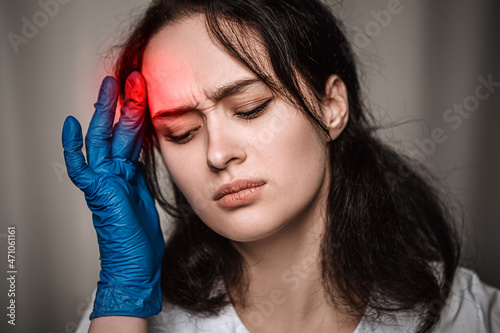 Nurse worker have headache migraine close eyes feel bad pain tired owerworked stressed touching temples. Female doctor dressed medical white gown blue sterile rubber gloves, healthcare overwhelmed
 photo