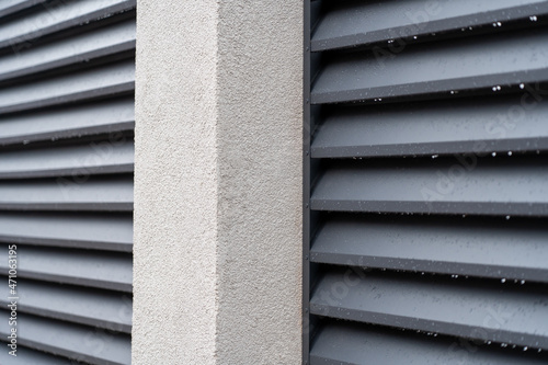 Close up of corrugated metal fence, horizontal modern metal fence with grey stucco column. Modern metal profile fence with shutters or blinds photo