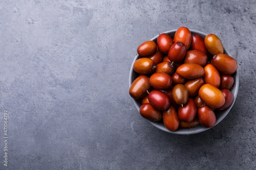 Obraz premium Ripe red dates in bowl on grey table, top view. Space for text
