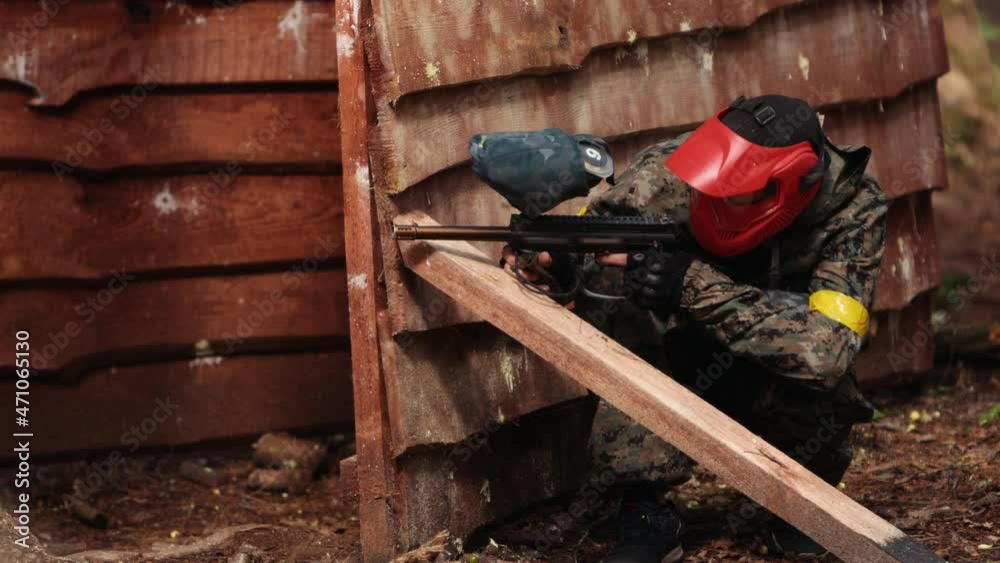 Paintball sport player wearing protective mask shooting. Player in uniform Paintball sport player wearing protective mask shooting. Player in uniform