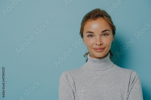 Portrait of smiling woman with makeup and healthy glowing skin dressed in grey poloneck photo