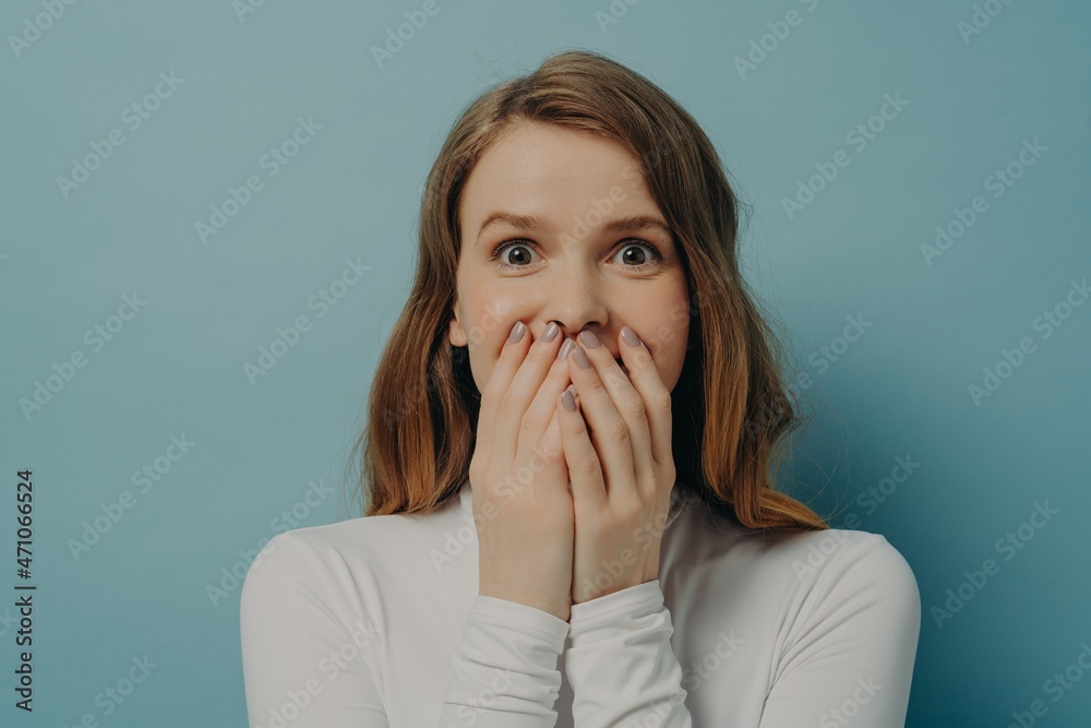 Charming surprised positive young woman closing her mouth with both hands in excitement Charming surprised positive young woman closing her mouth with both hands in excitement