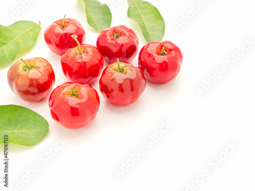 Pile of ripe red acerola cherries and green leaves isolated on a white background