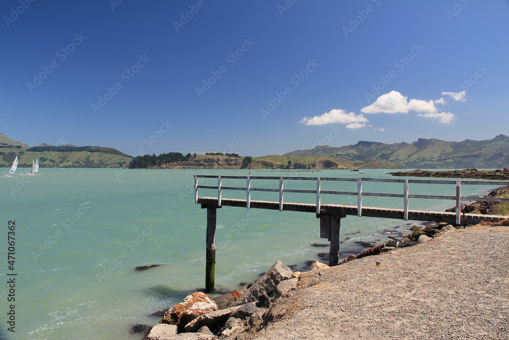 View of wooden jetty with sailing activity on weeked in Lyttelton Harbour in South Island, New Zealand