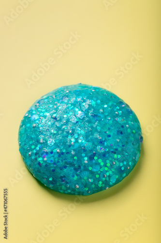 Blue glitter slime on yellow background. fun sensory toy for kids. vertical image