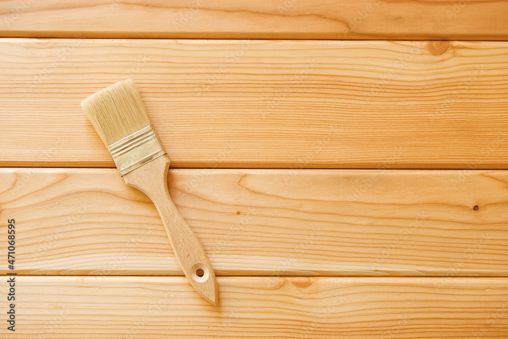 Paint brush with bristles and a wooden handle on natural wooden boards. Top view. Copy, empty space for text