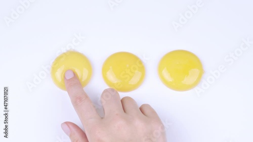 Video of female finger trying break egg yolk photo