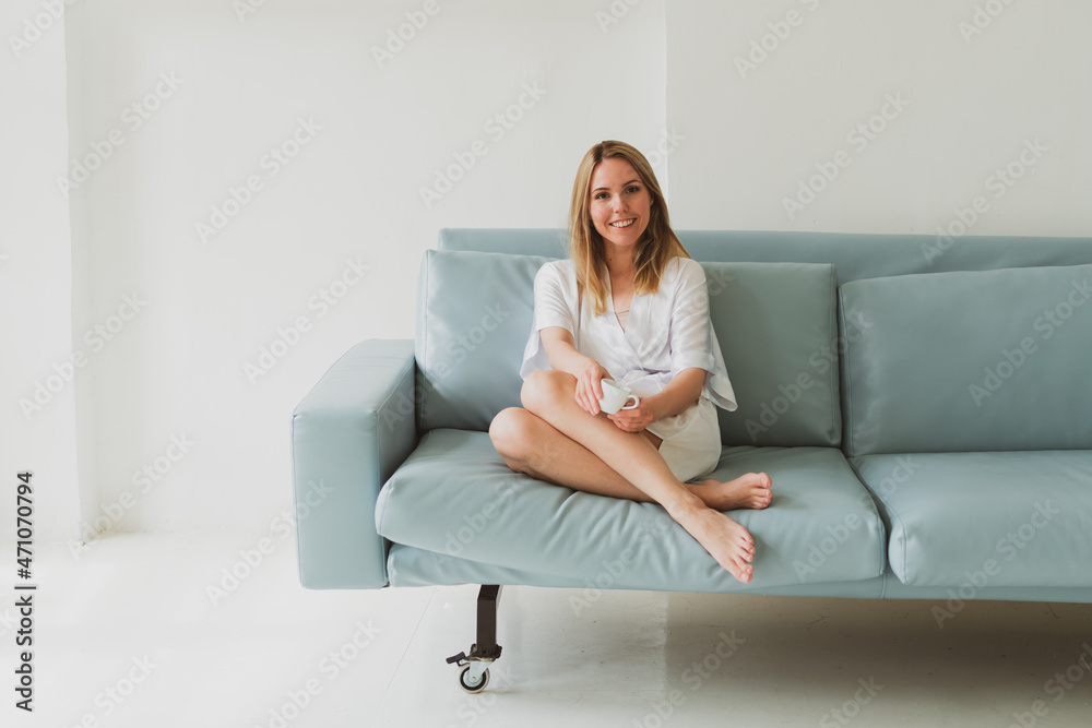 portrait of a young charming woman in a silk robe with cup of coffee at home on the sofa portrait of a young charming woman in a silk robe with cup of coffee at home on the sofa